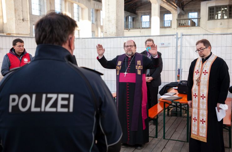 Weihbischof Wolfgang Bischof spendet den Segen in der Ankunftshalle für geflüchtete Menschen in Freilassing
