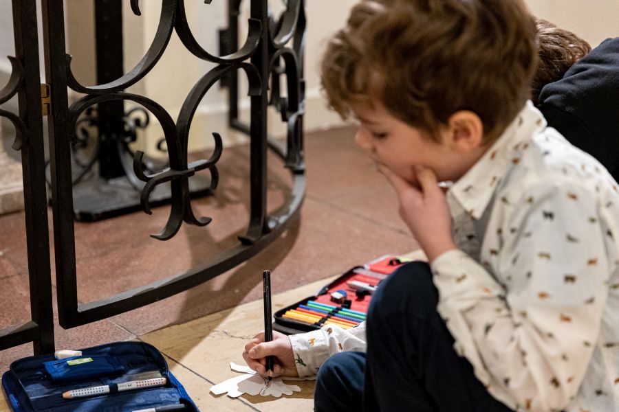 Ein Schüler der Klasse 1b der Franziskus-Grundschule beschriftet eine Papier-Friedenstaube