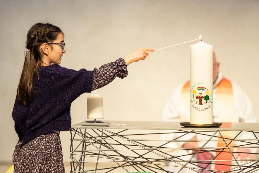Eine Schülerin der Franziskus-Grundschule entzündet eine Kerze im Wortgottesdienst in der Campuskirche