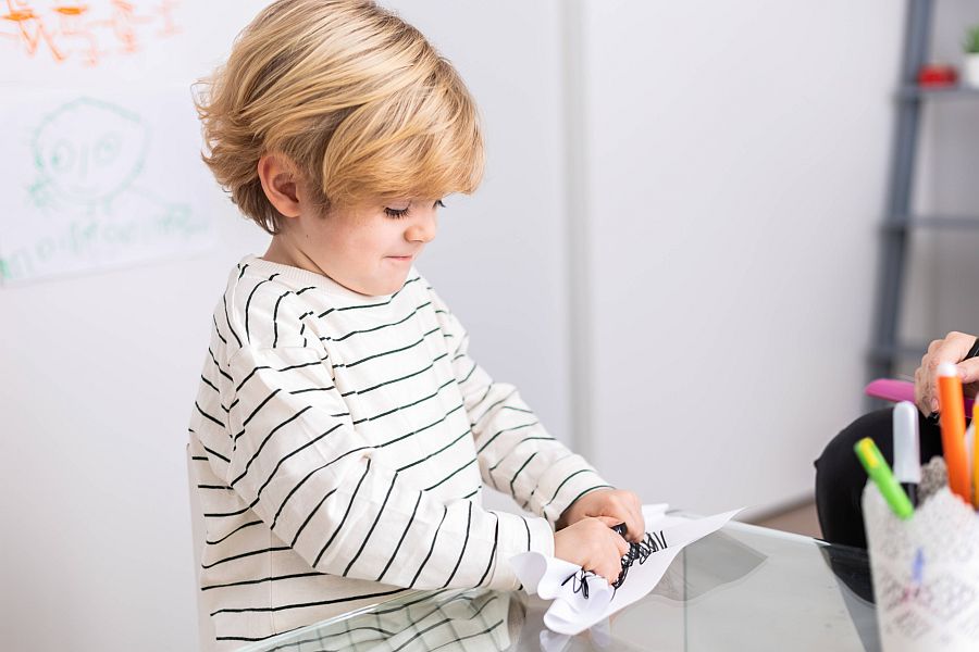 Wütendes Kind zerknüllt bemaltes Papier auf Schreibtisch