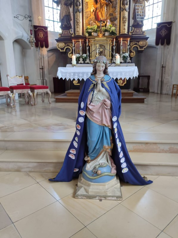 Marienfigur mit Stoffumhang, in den Kindergesichter geklebt wurden.