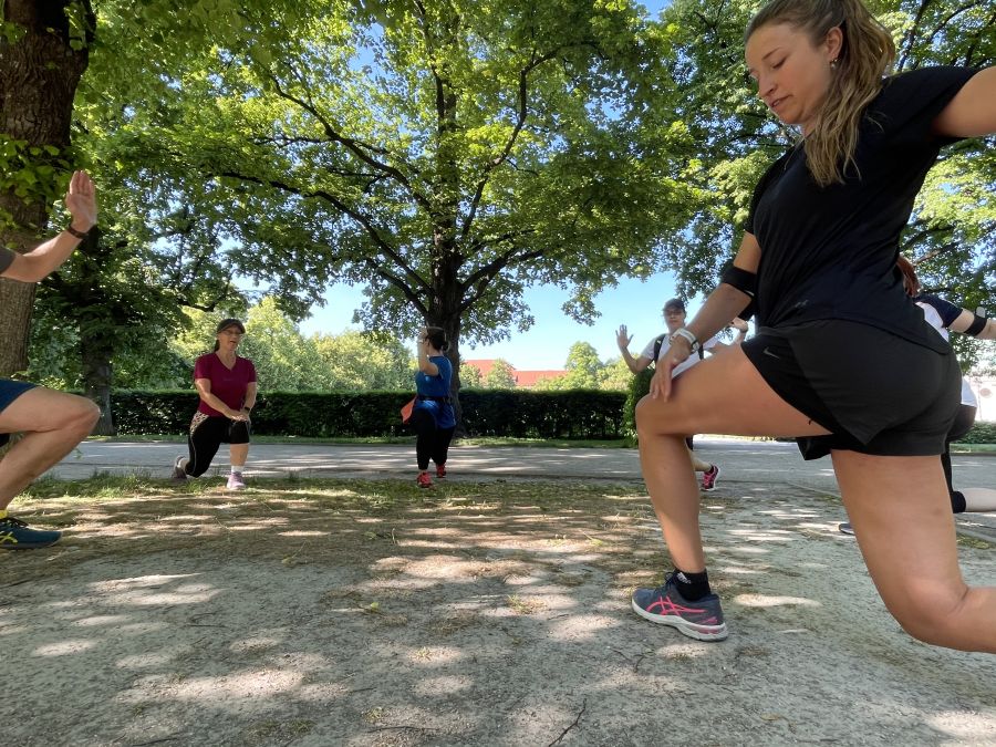 Die Teilnehmenden der Laufgruppe des Erzbischöflichen Ordinariats München dehnen sich vor dem Training im Hofgarten vor der Residenz