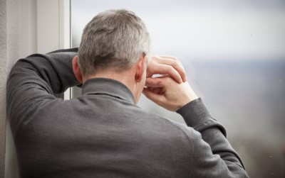 Trauriger Mann schaut aus dem Fenster