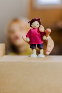 Kind zeigt Handpuppe zwischen Kartons