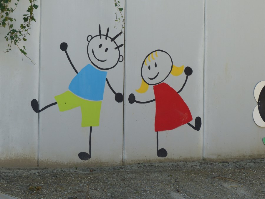 fröhliche Strichmännchen an der Gartenmauer des Kindergartens, die sich an der Hand halten