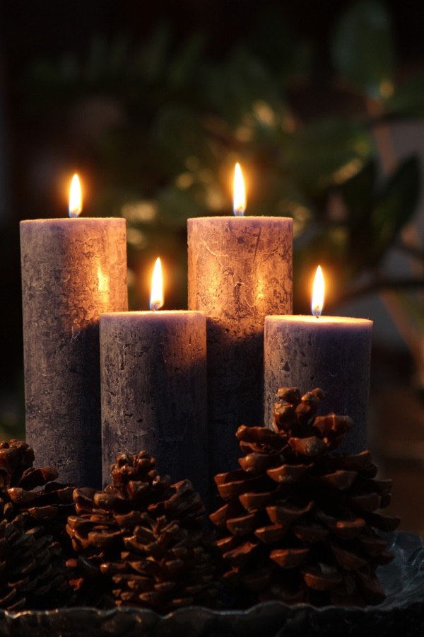 Auf dem Foto sind vier brennende Adventskerzen auf einem Adventskranz zu sehen.