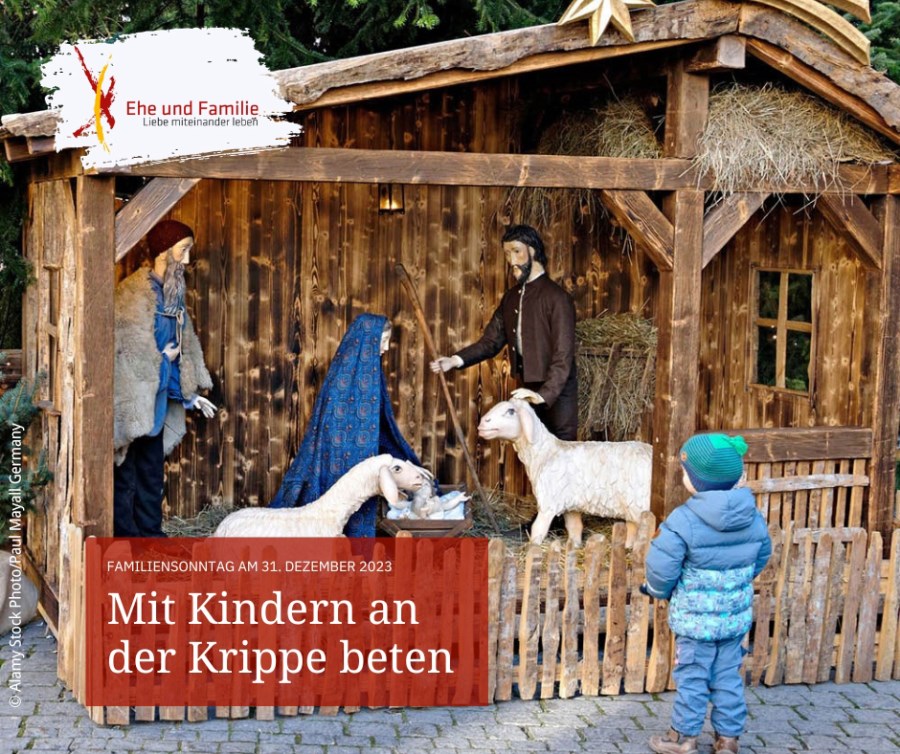 Auf dem Foto ist ein Kind zu sehen, das vor einer Krippe im Freien steht.