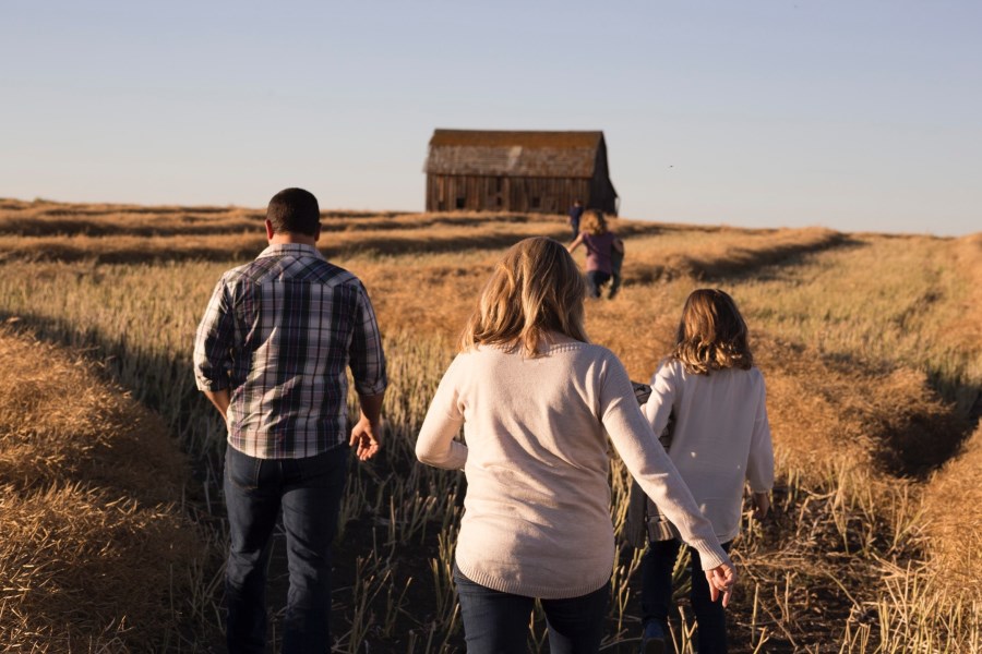 Auf dem Foto ist eine Familie von Hinten in einem Kornfeld zu sehen, die spazieren geht.