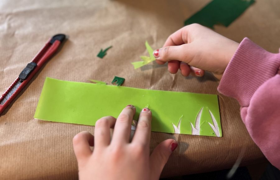 Kind bastelt die Applikation Blume für die Osterkerze 2024