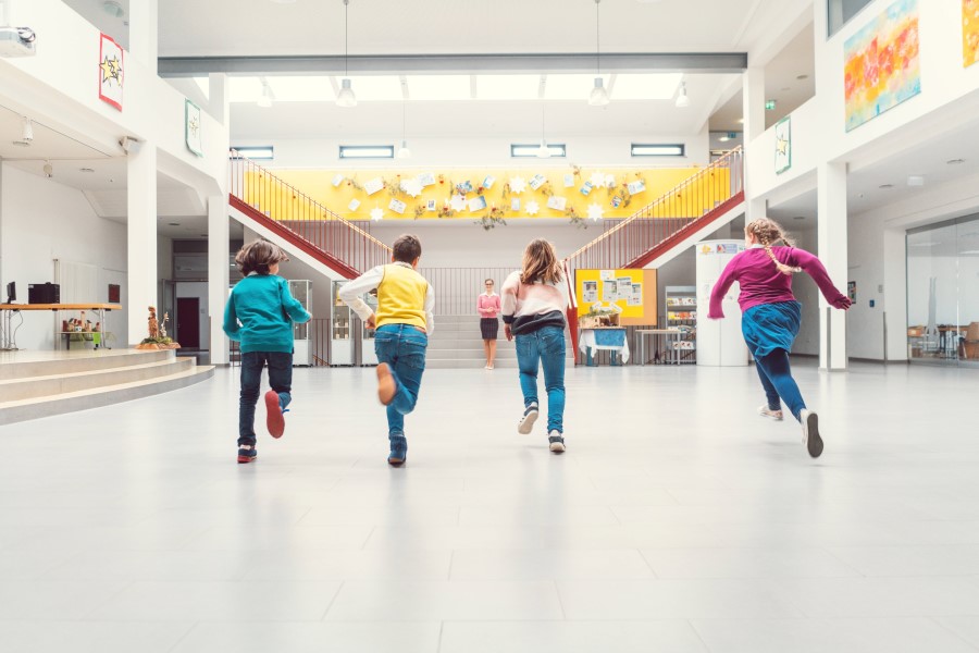Grundschulkinder rennen auf Lehrerin zu