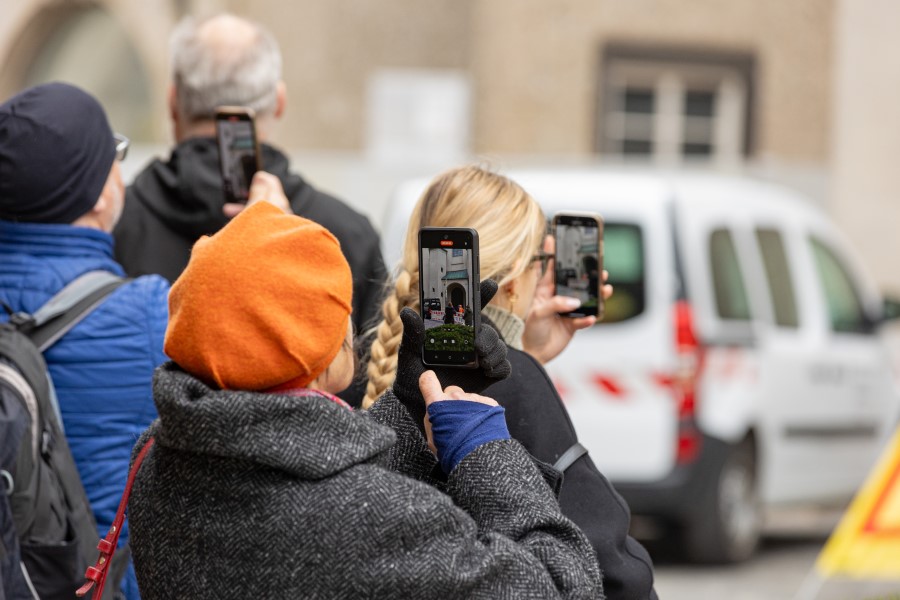 Passanten filmen das Aufhängen der Zeiger am Alten Peter