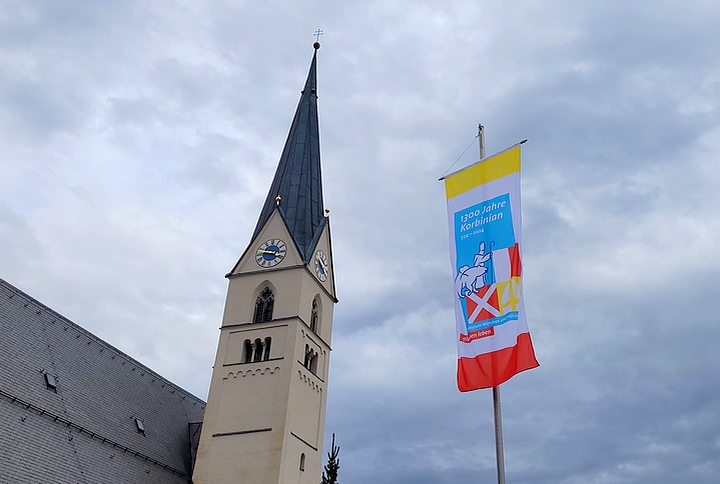 Pfarkirche St. Martin in Babensham mit Fahne anlässlich des Bistumsjubiläums „1300 Jahre Korbinian“