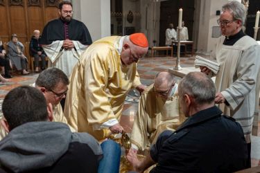 Kardinal Reinhard Marx wäscht einem ukrainischen Flüchtling die Füße während der Messe zum Letzten Abendmahl im Münchner Liebfrauendom