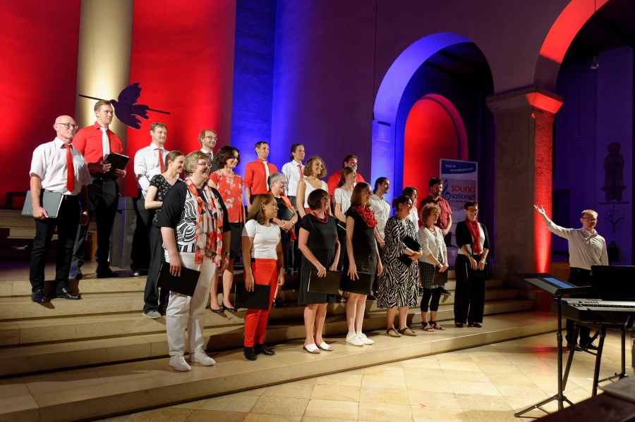 Der Chor Soundsationell mit Dirigent im Altarraum bei Applaus