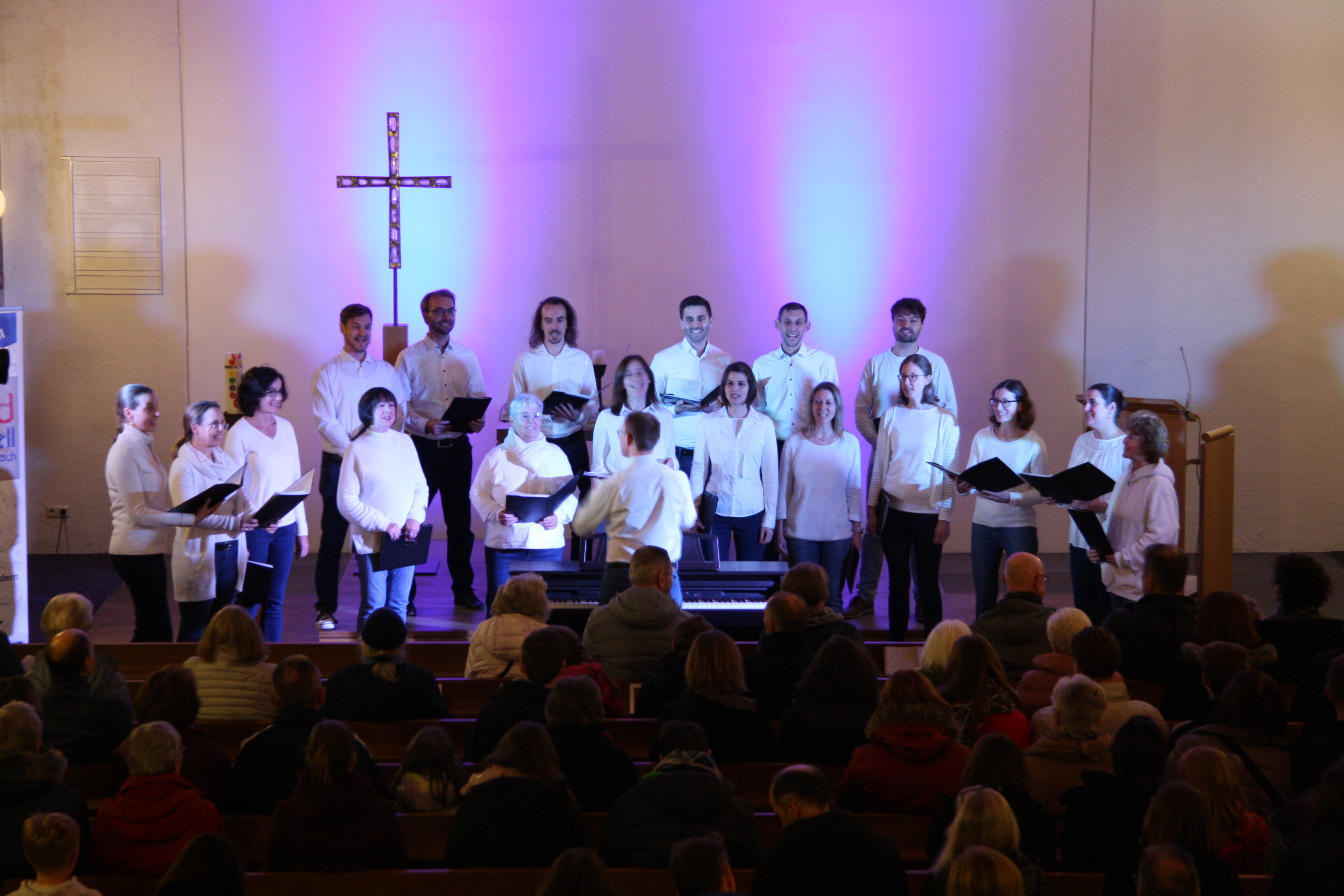Chor soundsationell in der Heilig Geist Kirche. Chorsängerinnen und Sänger mit weißen Hemden. Raum ist rot ausgeleuchtet