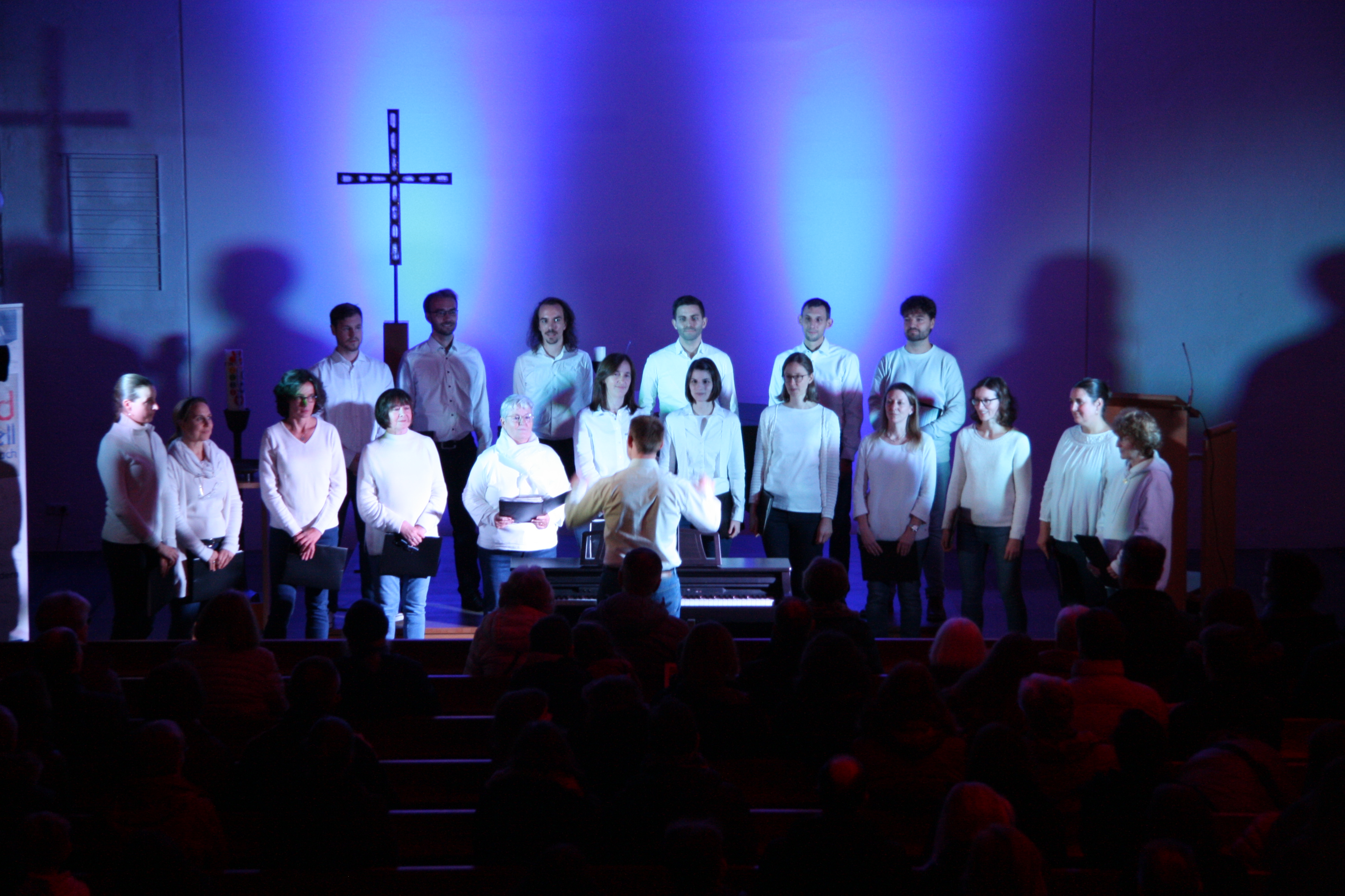 Sängerinnen und Sänger des Chors sounsationell beim Auftritt in der Heilig-Geist Kirche. Der Raum ist blau ausgeleuchtet.