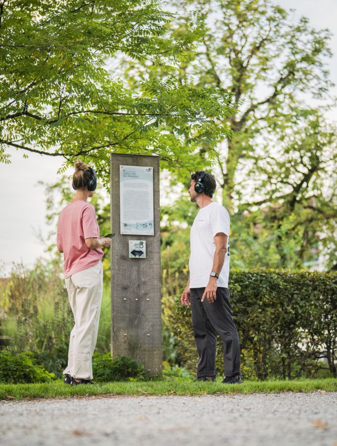 Ein Paar schaut gemeinsam auf eine Informationsstele am Waldrand