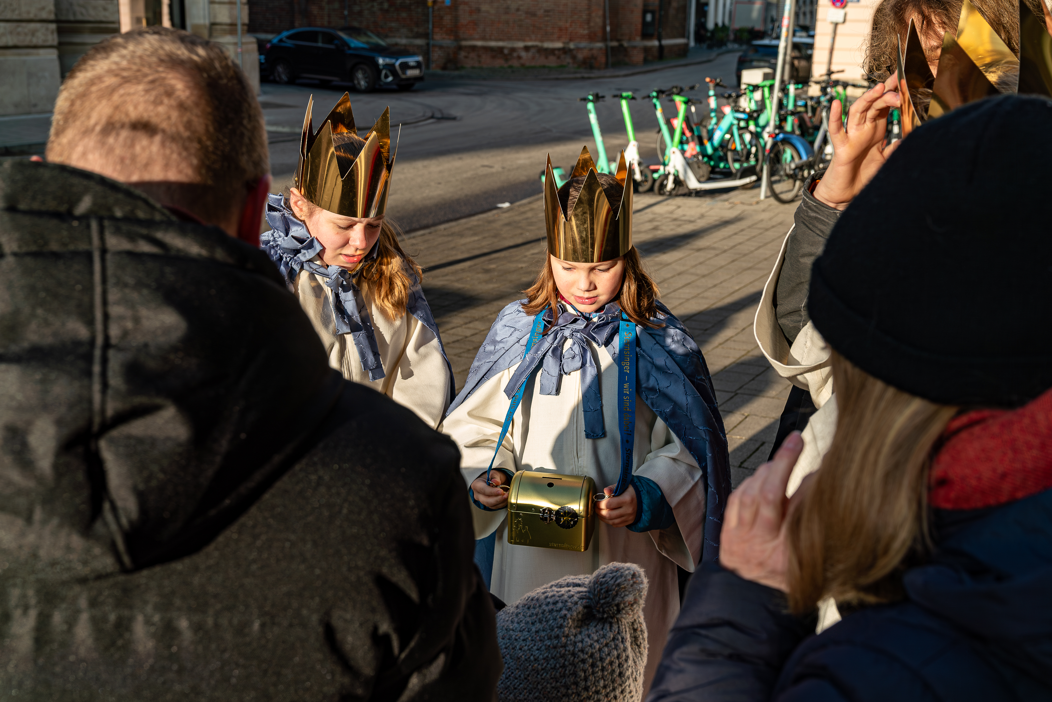 Die Sternsinger stehen im Kreis, ein Mädchen hält eine Sammeldose