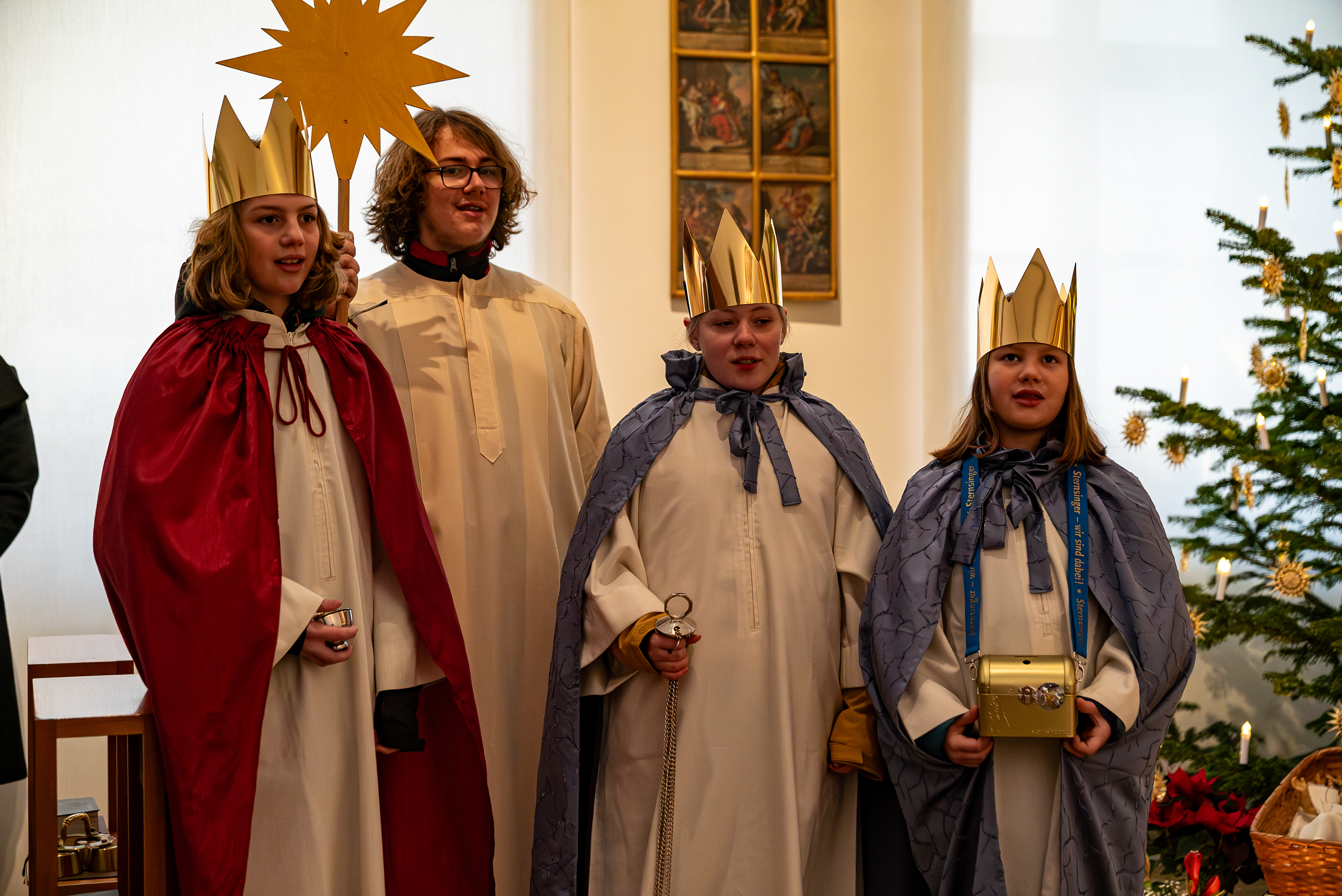 Die Sternsinger stehen gemeinsam mit dem Sternträger in einer Reihe