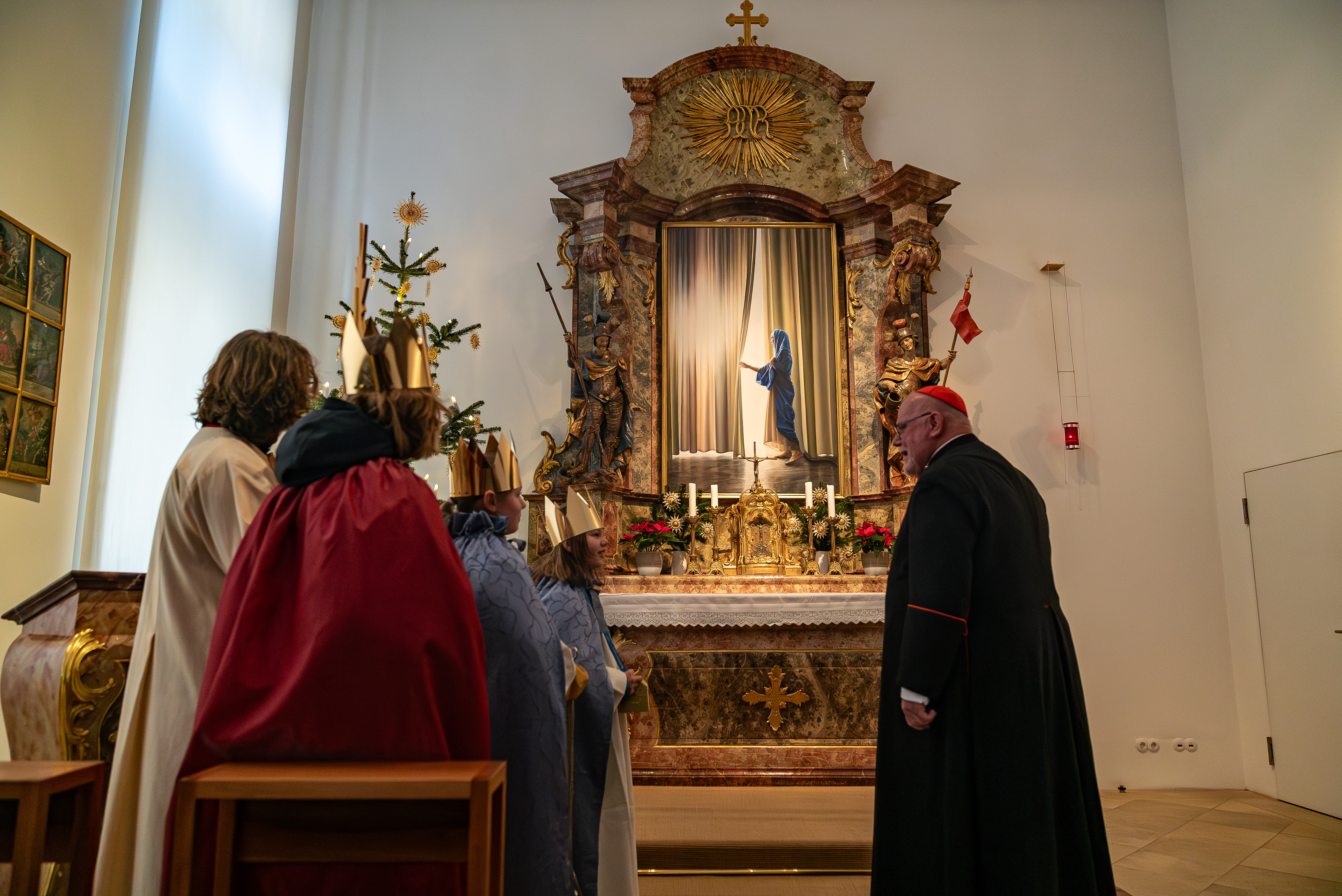 Die Sternsinger und der Kardinal betrachten den Altar in der Hauskapelle