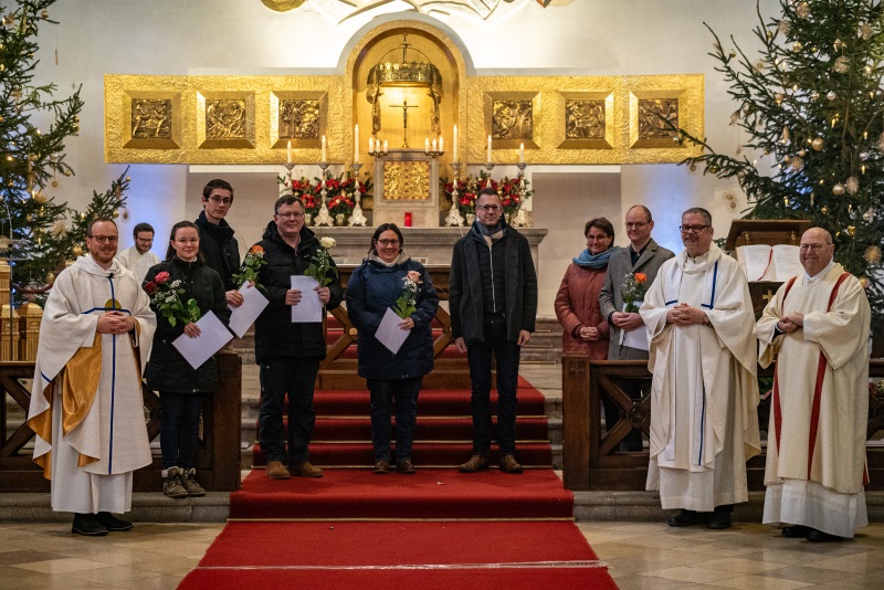 Die neuen Kommunionhelfer und Lektoren mit Blumen und Urkunden vor dem Altar von Maria Schutz