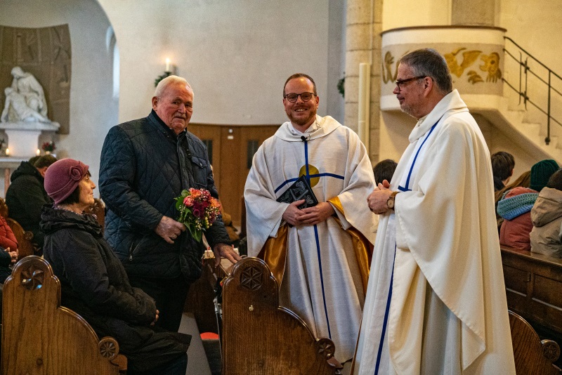 Lorenz Strohmeier mit Blumen und Pfarrer Emslander sowie Pfarrvikar Spielauer