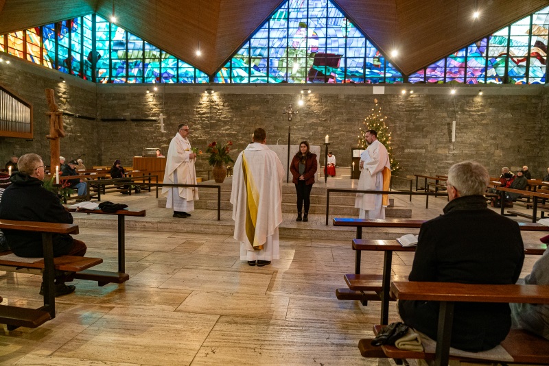 Pfarrer Emslander von hinten segnet die neue Kommunionhelferin in St. Hildegard
