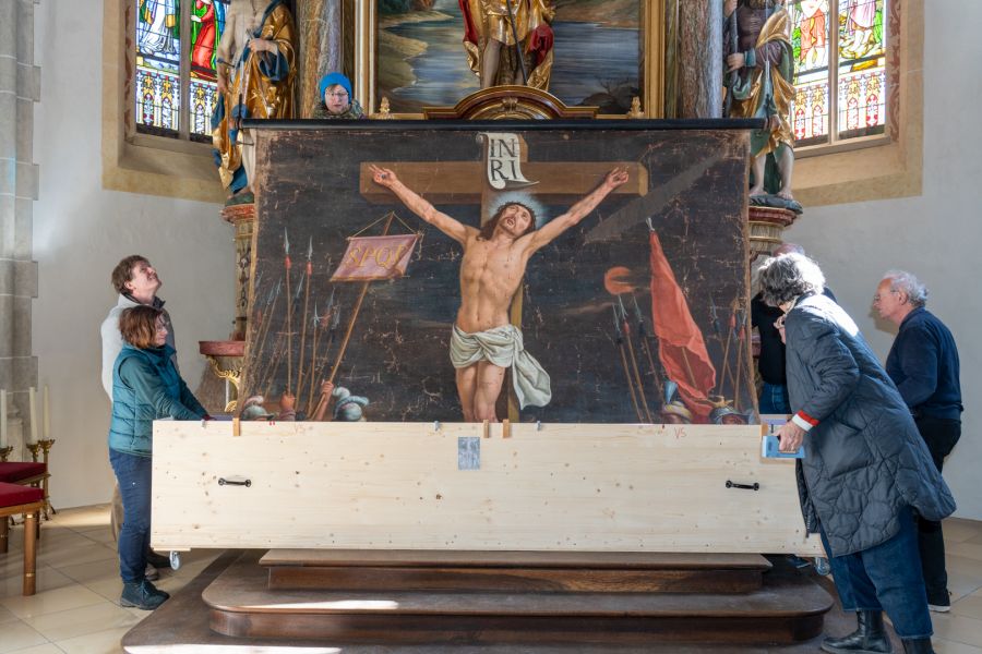 Das restaurierte Fastentuch wird vor dem Altarbild in St. Johann Baptist in Oberwarngau entrollte