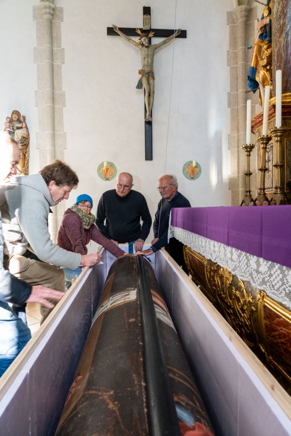 Das restaurierte Fastentuch wird per Seilwinde aus der Transportkiste vor das Altarbild von St. Nepomuk in Oberwangau gezogen.