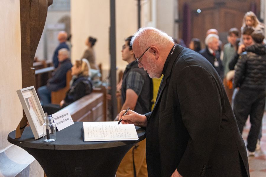 Kardinal Reinhard Marx trägt sich in das im Münchner Liebfrauendom ausliegende Kondolenzbuch für Papst Franziskus ein.