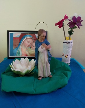 Marienfigur und Bild auf blauem Tuch und Blumen