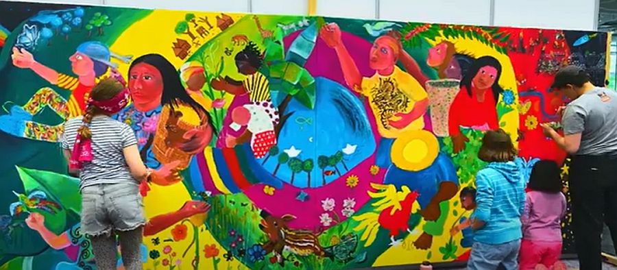 Zwei Künstler malen ein buntes Mural-Gemälde, während zwei Kinder zusehen