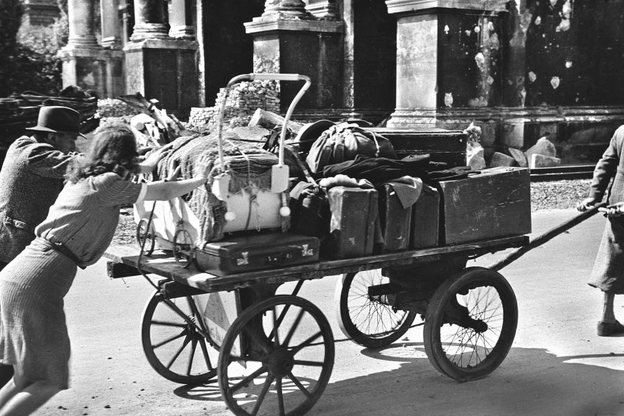Flüchtlinge schieben und ziehen einen Karren am 13. Juli 1945 am Siegestor in München vorbei.
