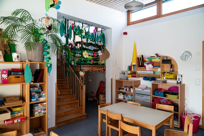 Gruppenzimmer mit Stühlen und Tisch, Bücherregal und Spielhöhle in der Kita St. Quirin