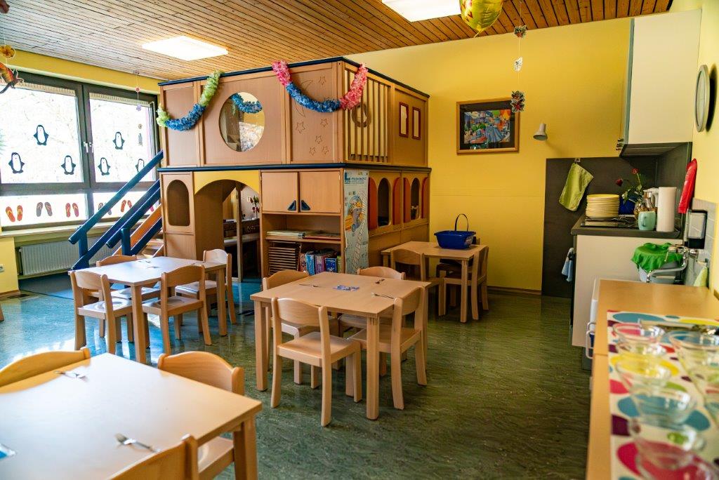 Gruppenraum mit Spielhaus, Tischen und Stühlen davor im Kinderhaus Maria Schutz