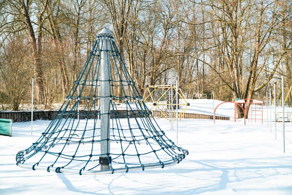 Kletterkarusell und Klettergerüste im verschneiten Garten des Kinderhauses Maria Schutz