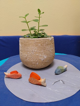 Fischi auf einem blauen Tuch vor einem Blumenstock