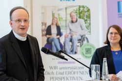 Generalvikar Christoph Klingan (l.) und Edda Hamm vor einem Plakat der Arbeitgebermarke