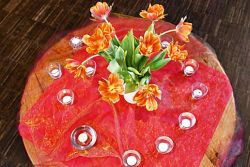 Tisch mit roter Tischdecke, orangefarbenen Blumen und Kerzen