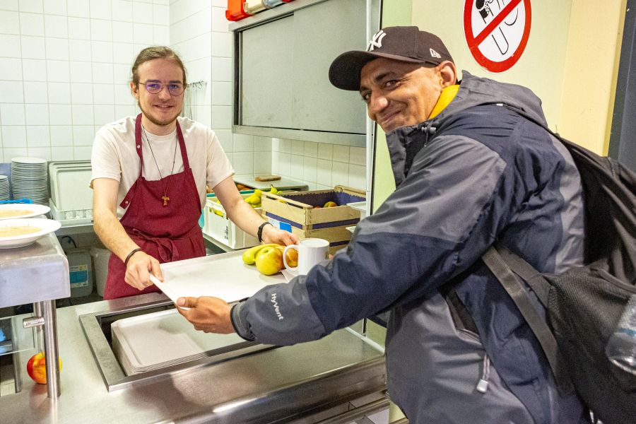 Student Florian Meidinger gibt bei seinem Praktikum in der Obdachlosenhilfe in Sankt Bonifaz ein Essen an einen Obdachlosen aus