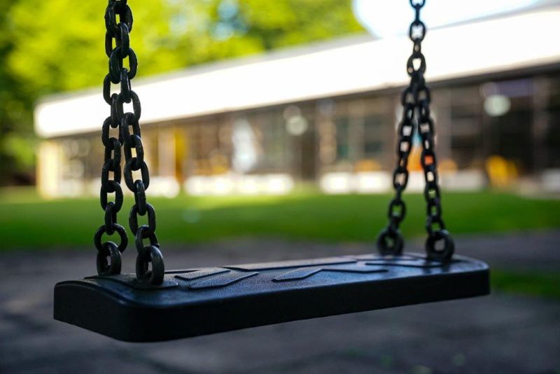 Einzelner Schaukelsitz, dahinter (unscharf) der Flachbau der Kita St. Markus