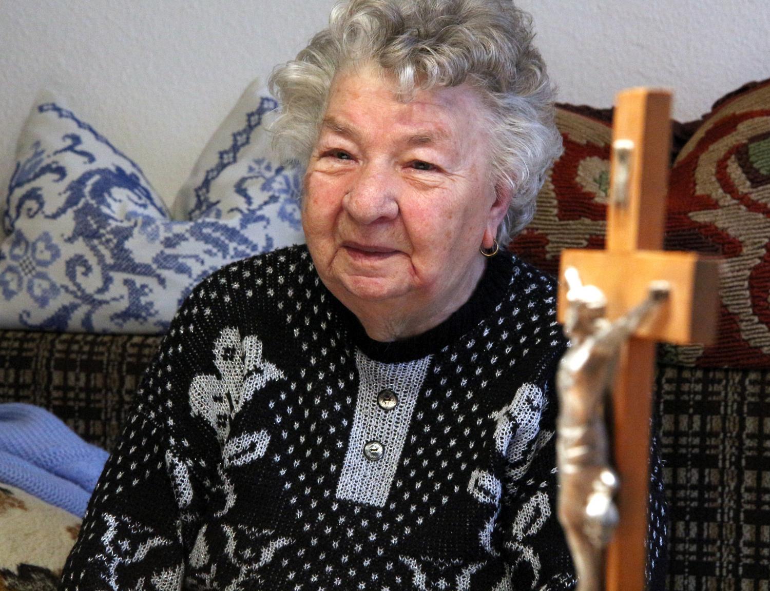 Eine betagte Frau und ein geschnitztes Kreuz