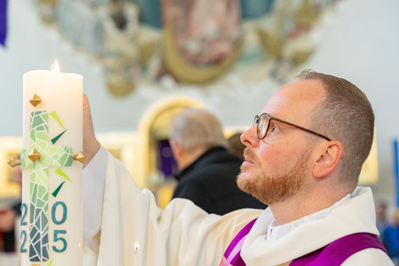 Pfarrer Emslander entzündet das Feuer für die Altarweihe an der Osterkerze