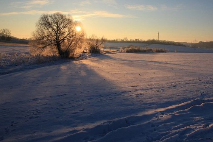 Untergehende Sonne über verschneiter Winterlandschaft