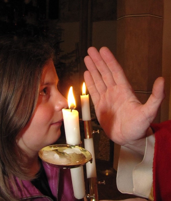 Mädchen erhält den Blasius-Segen mit zwei gekreuzten Kerzen