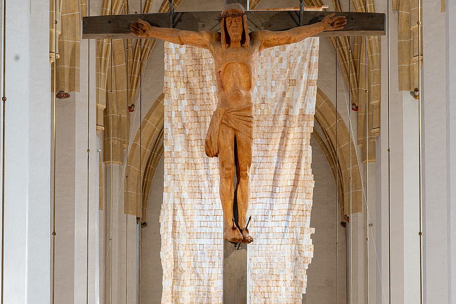 Das aus Teebeuteln zusammen genähte Kunstwerk „Cartografía inconclusa / Unfinished Cartography“ von Lisa Granada hängt in der Münchner Liebfrauenkirche hinter dem Kreuz