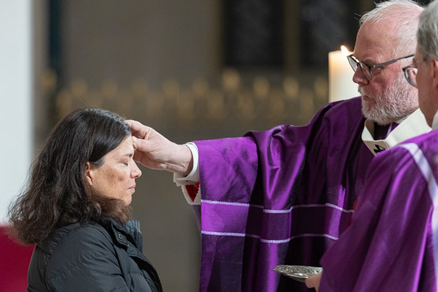 Kardinal Reinhard Marx spendet einer Frau das Aschenkreuz beim Gottesdienst im Münchner Liebfrauendom am 18. Februar 2026