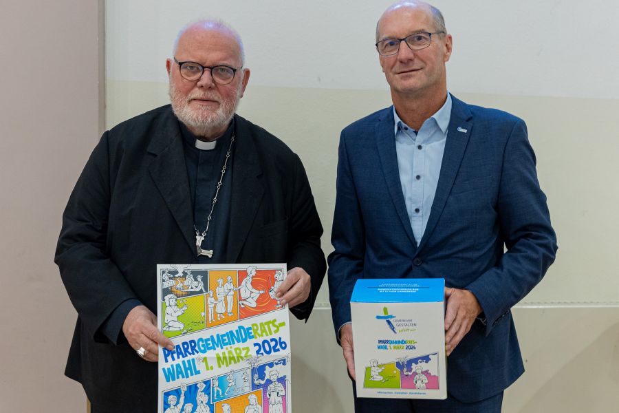 Kardinal Reinhard Marx (links) und der Diözesanratsvorsitzende Armin Schalk halten ein Plakat und eine Wahlurne zur Pfarrgemeinderatswahl in Händen
